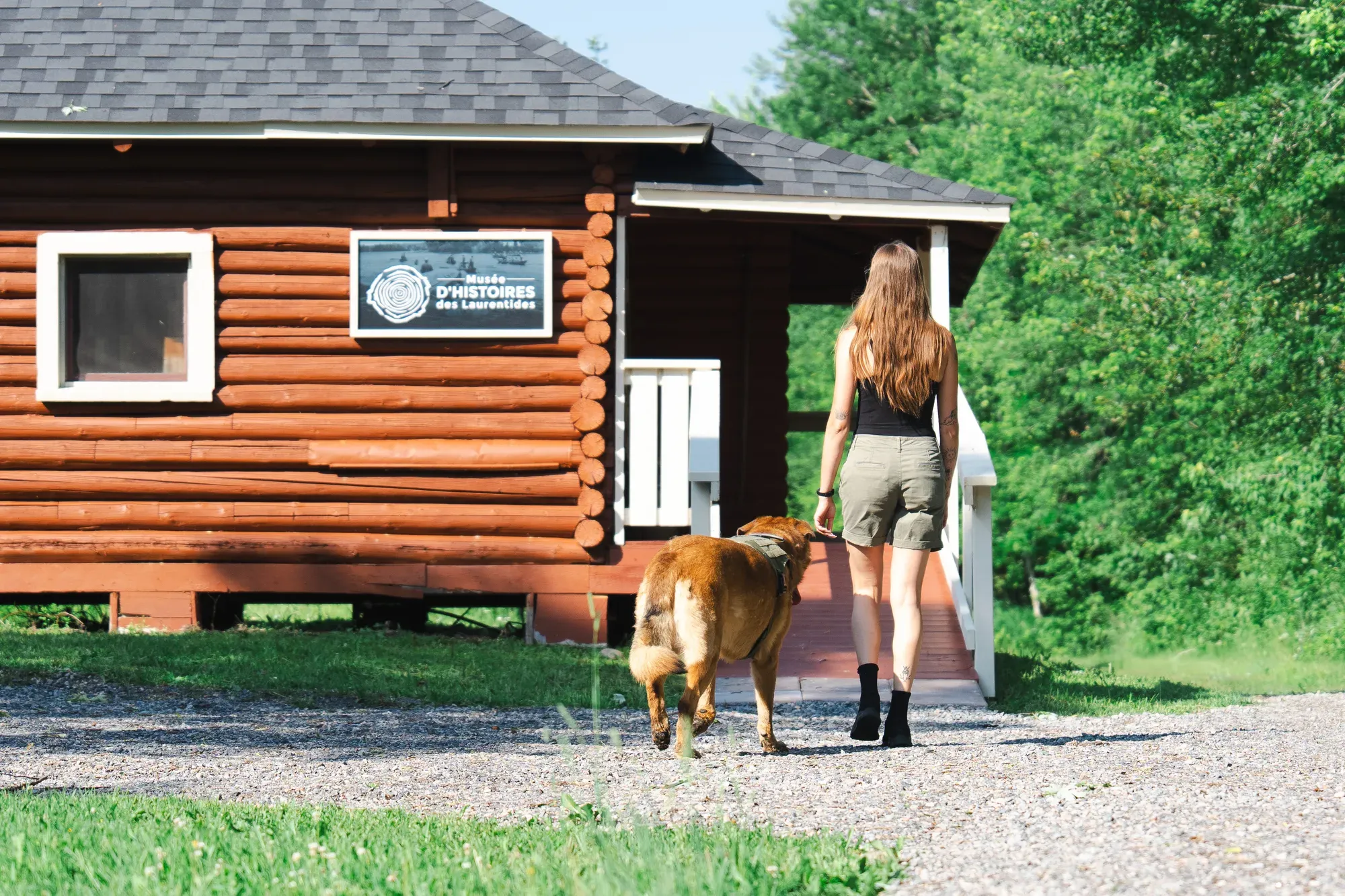 Une visiteuse et son chien arrivent au pavillon du Musée d'histoires des Laurentides